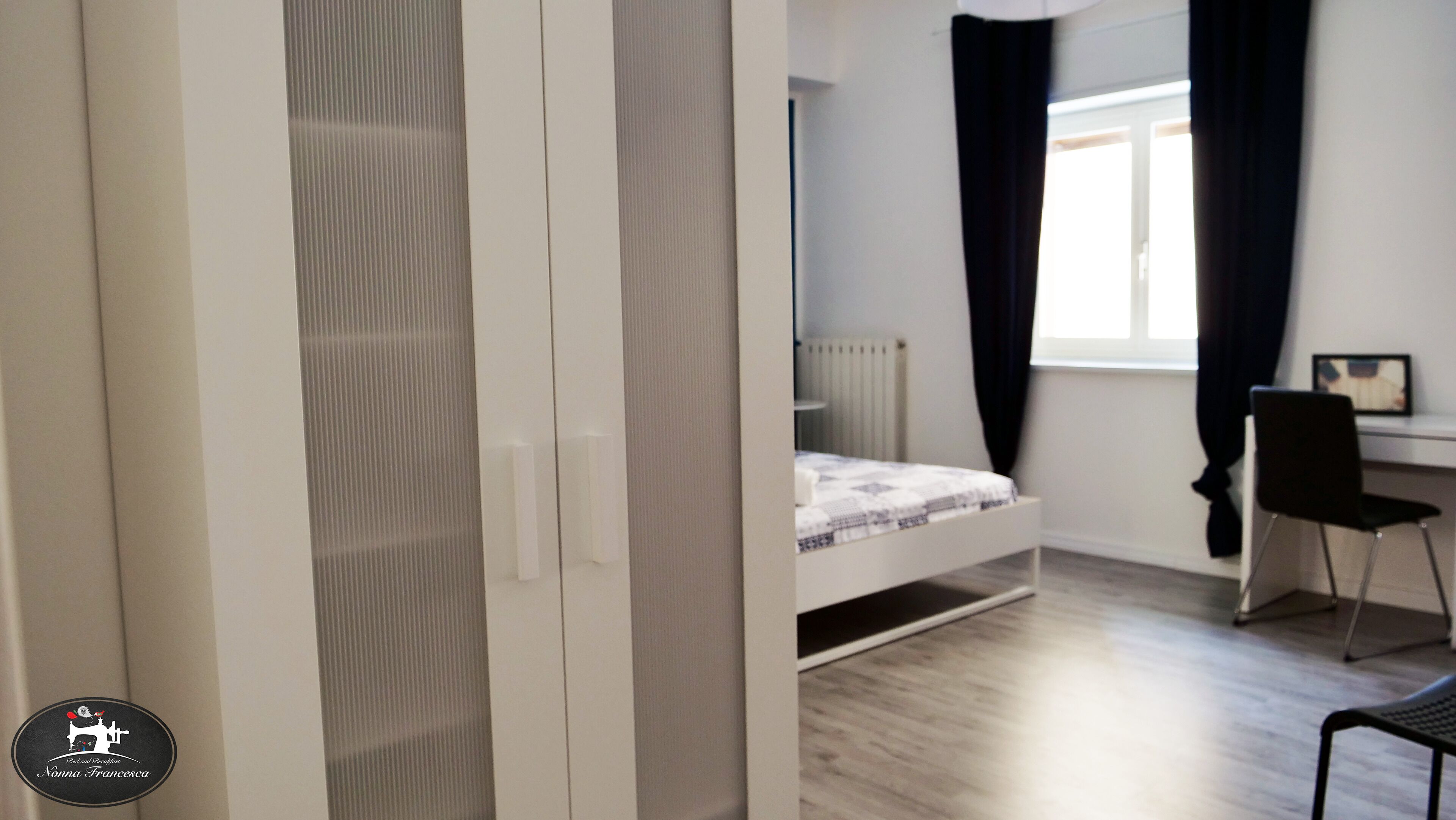 A bedroom with a bed, a desk, and a chair.