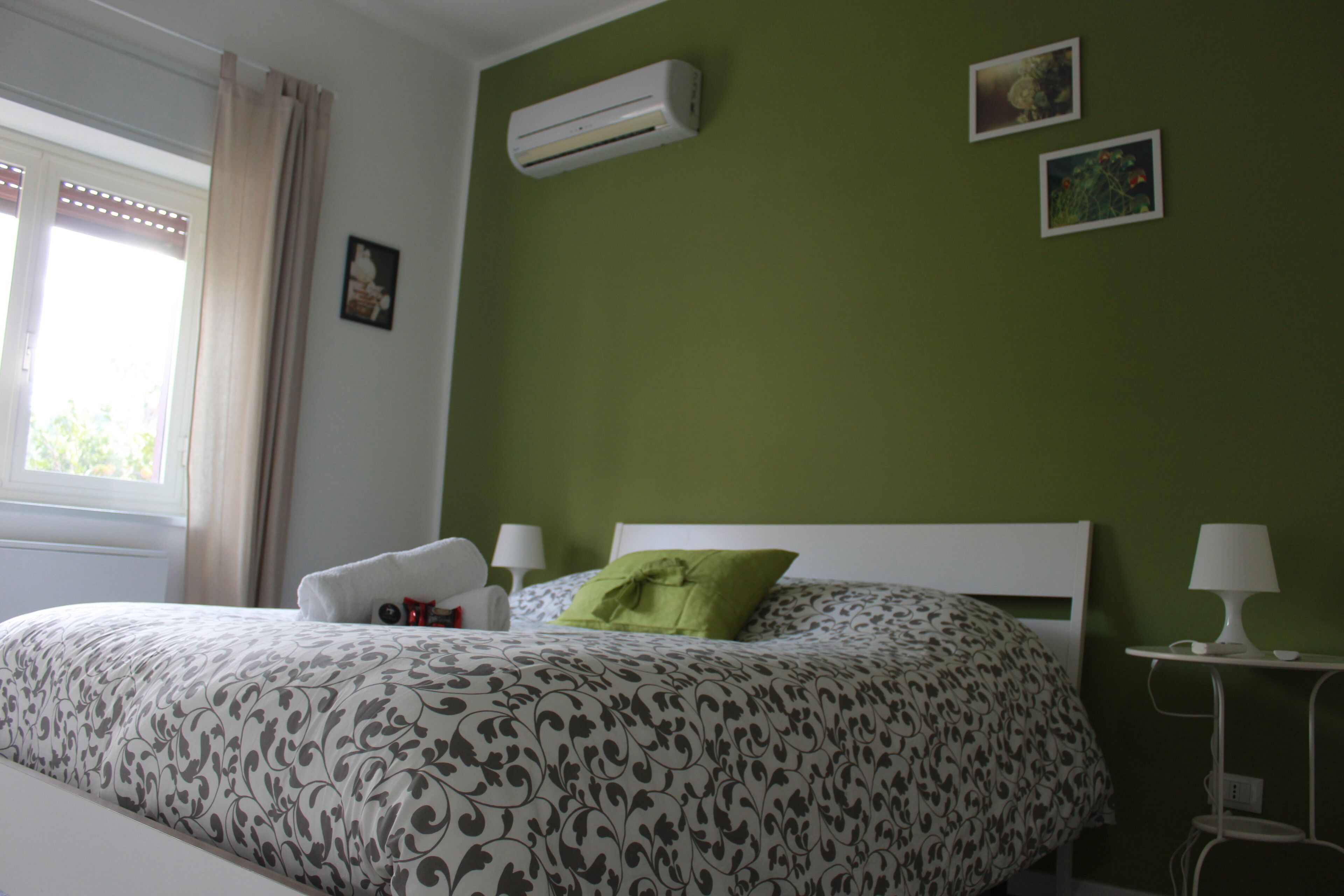 Une chambre à coucher comprenant un lit, une table de chevet, une lampe et un climatiseur fixé au mur.