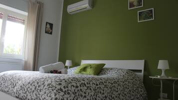 Une chambre à coucher comprenant un lit, une table de chevet, une lampe et un climatiseur fixé au mur.