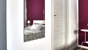 Un dormitorio con una cama, una mesita de noche y otra mesita auxiliar.
