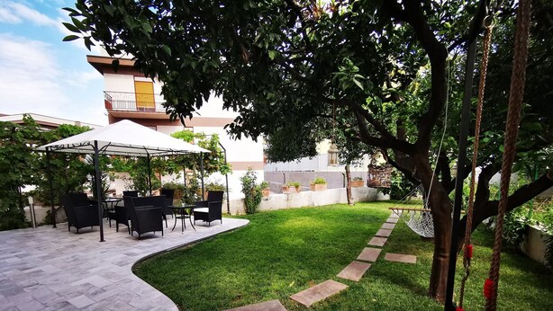 Un patio con mobiliario exterior, una hamaca y un sendero en el jardín.