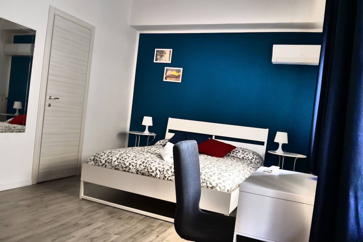 A bedroom with a bed, bedside tables, a mirror, and a wardrobe.