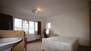 A bedroom with a bed, a desk, a chair, a window, and a radiator. - Draycott Guest House (Harrow)