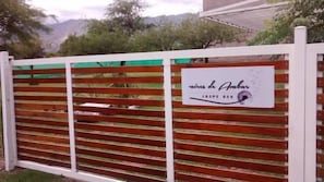 A white fence with horizontal slats and a sign that reads "Caminos de Ambar JASPE 859". - Aires de Ambar (Merlo)