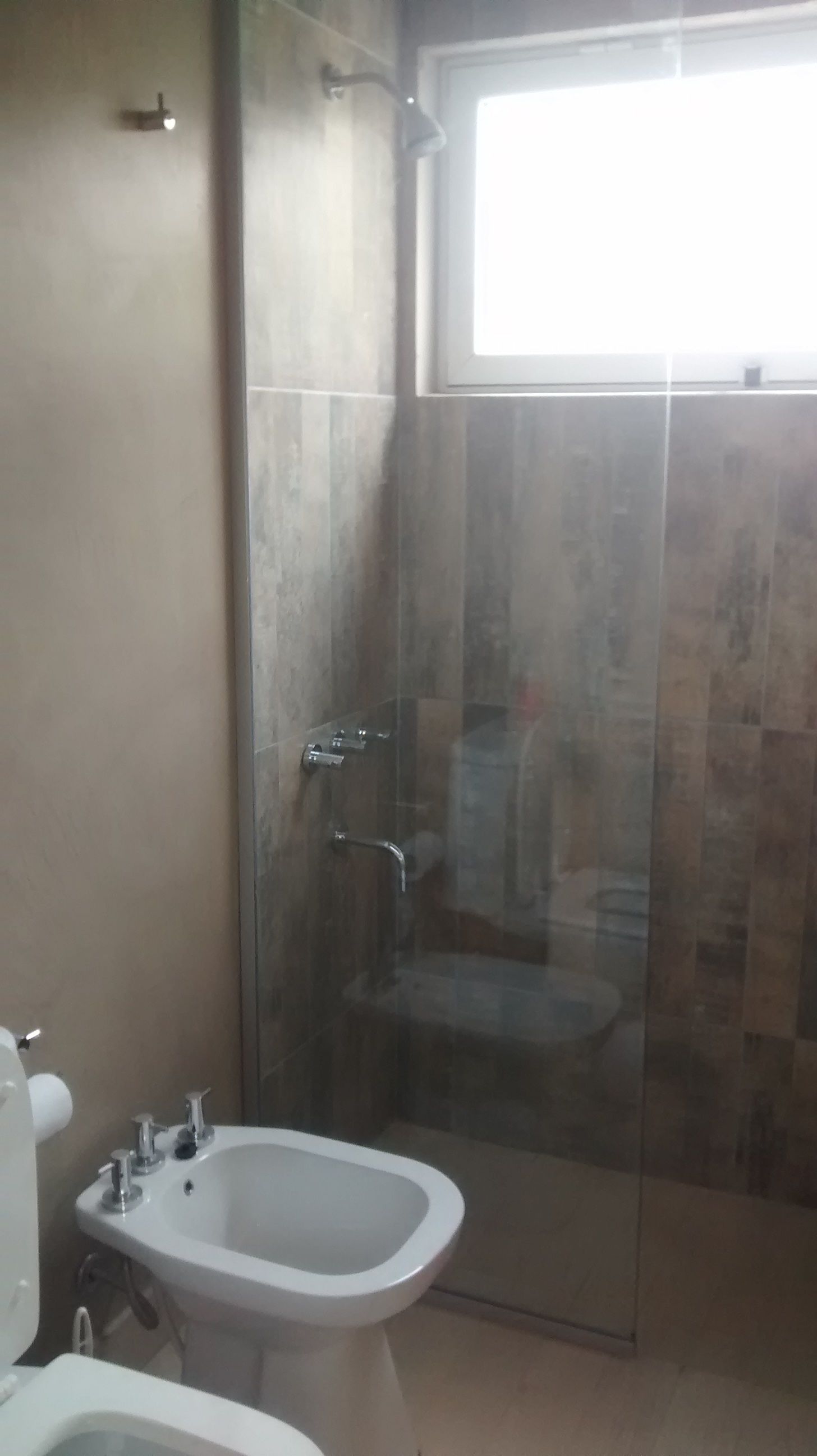 A bathroom with a glass-enclosed shower, a white sink, and a toilet.