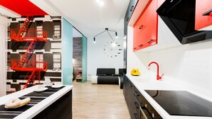 Une cuisine moderne avec un four noir, des plans de travail blancs et des touches de couleur rouge.