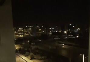 Vista nocturna desde una ventana que da a una calle con farolas y edificios.
