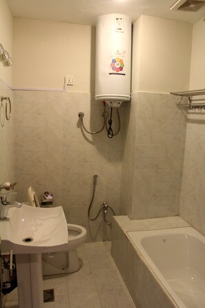 Un baño con inodoro, lavamanos, bañera y calentador de agua.
