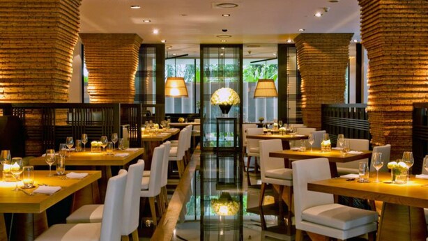 Un restaurante con una larga mesa central, sillas blancas y un suelo reflectante.