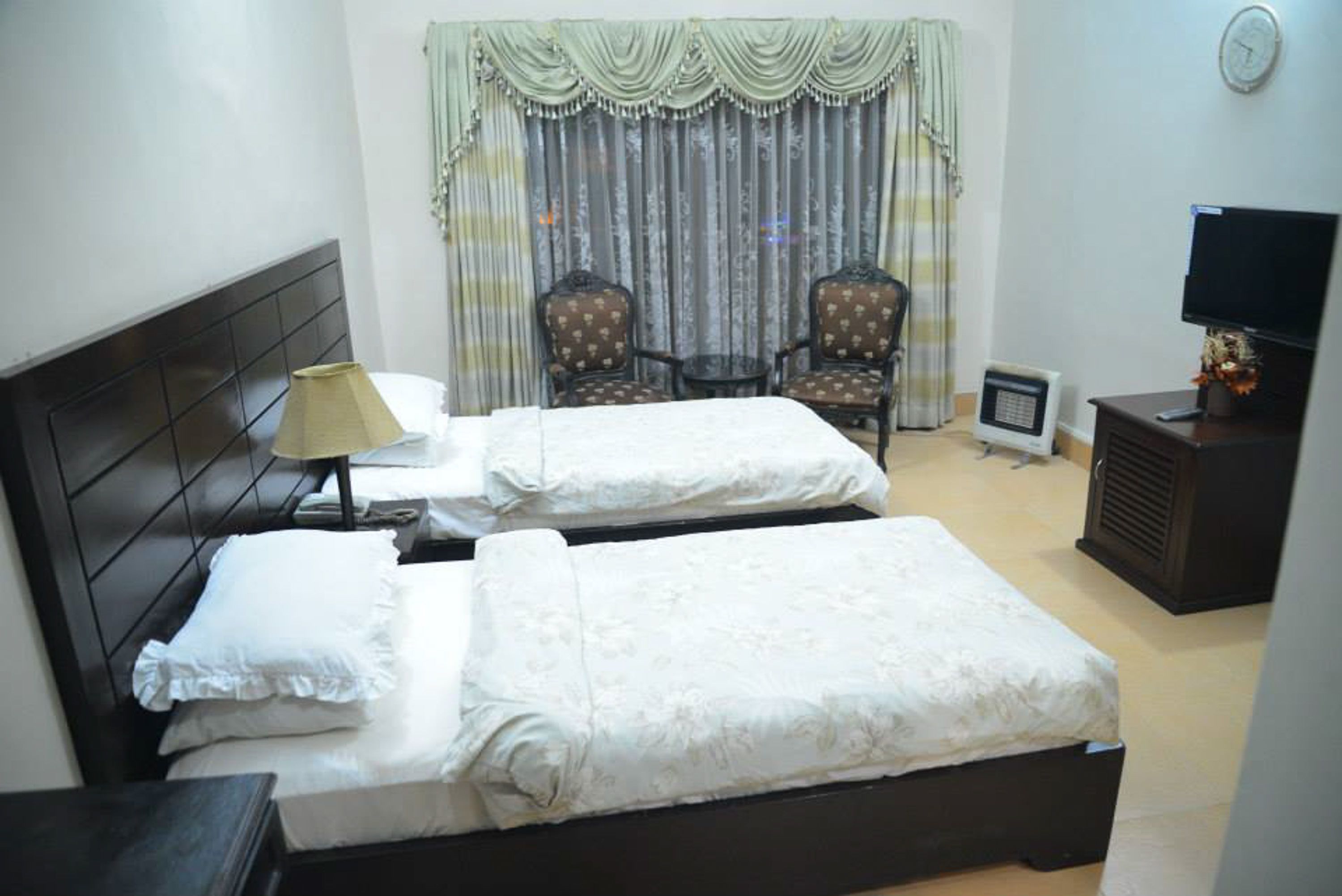 A hotel room with two beds, a TV, a small table, and a chair.