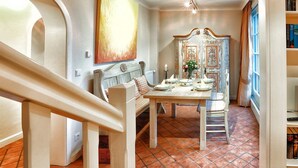 A dining area with a wooden table set for four, a bench, and a decorative mirror. - Ferienwohnung Biberhüs OG (Sylt)