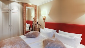 A hotel room with a large bed, white bedding, a red headboard, a mirror, and a wardrobe. - Ferienwohnung Sönshörn 8 Rechts (Sylt)