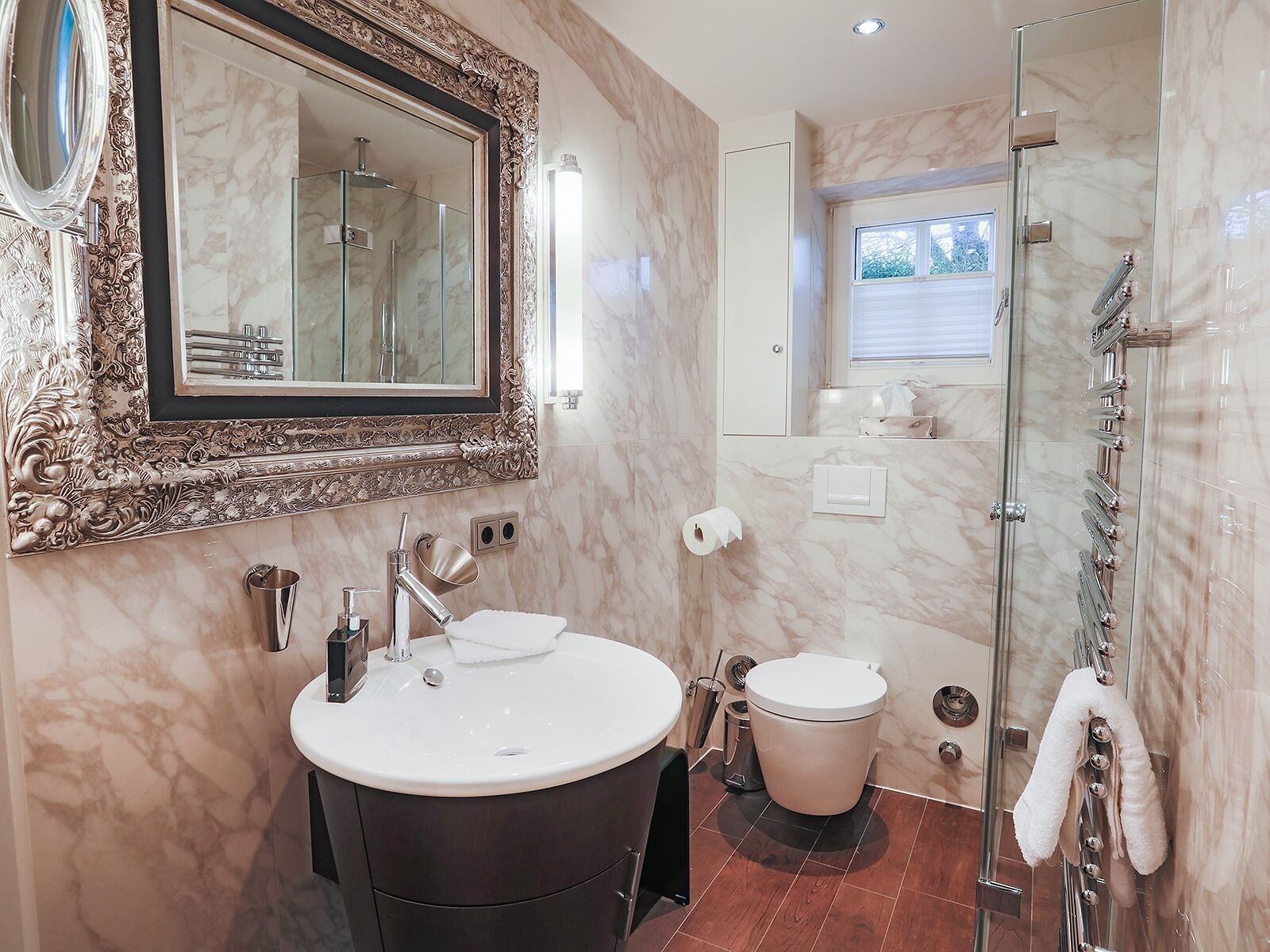 A bathroom with a marble vanity, a large mirror, a glass shower enclosure, and a toilet.