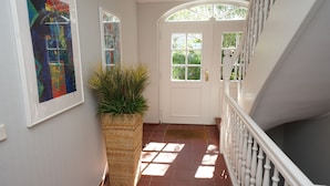 Ein Flur mit einer weißen Tür, einem Blumentopf und einer Treppe mit weißen Wangen.