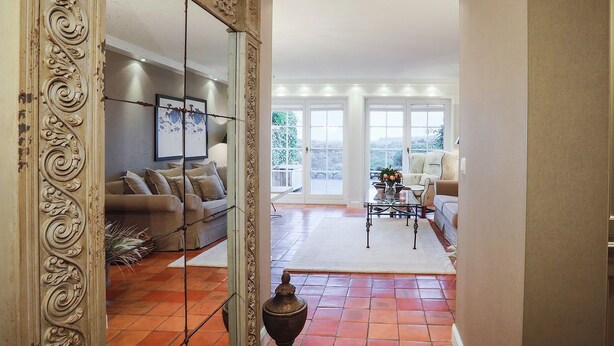 A spacious living room with a large window, a sofa, a coffee table, and a decorative urn. - Ferienwohnung Sönshörn 20 (Sylt)