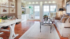 A spacious living room with a white coffee table, beige sofa, and a chandelier. - Ferienwohnung Sönshörn 20 (Sylt)