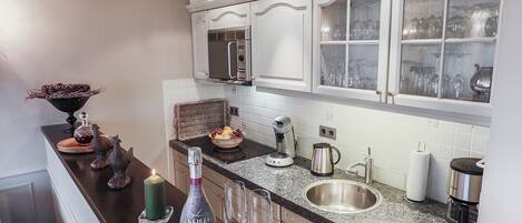 A modern kitchen with white cabinetry, a stainless steel sink, and a built-in oven.