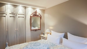 A bedroom with a large bed, a wardrobe, a mirror, and a nightstand with a lamp. - Ferienwohnung Sönshörn 8 Mitte (Sylt)
