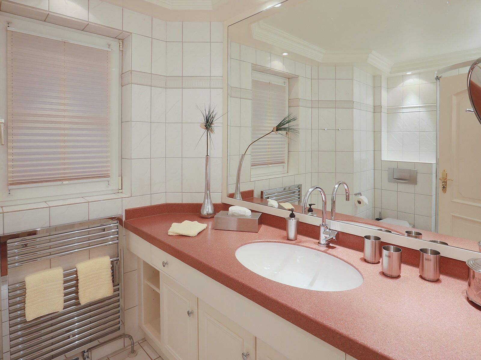 A modern bathroom with a large mirror, a white sink, and a towel rack.