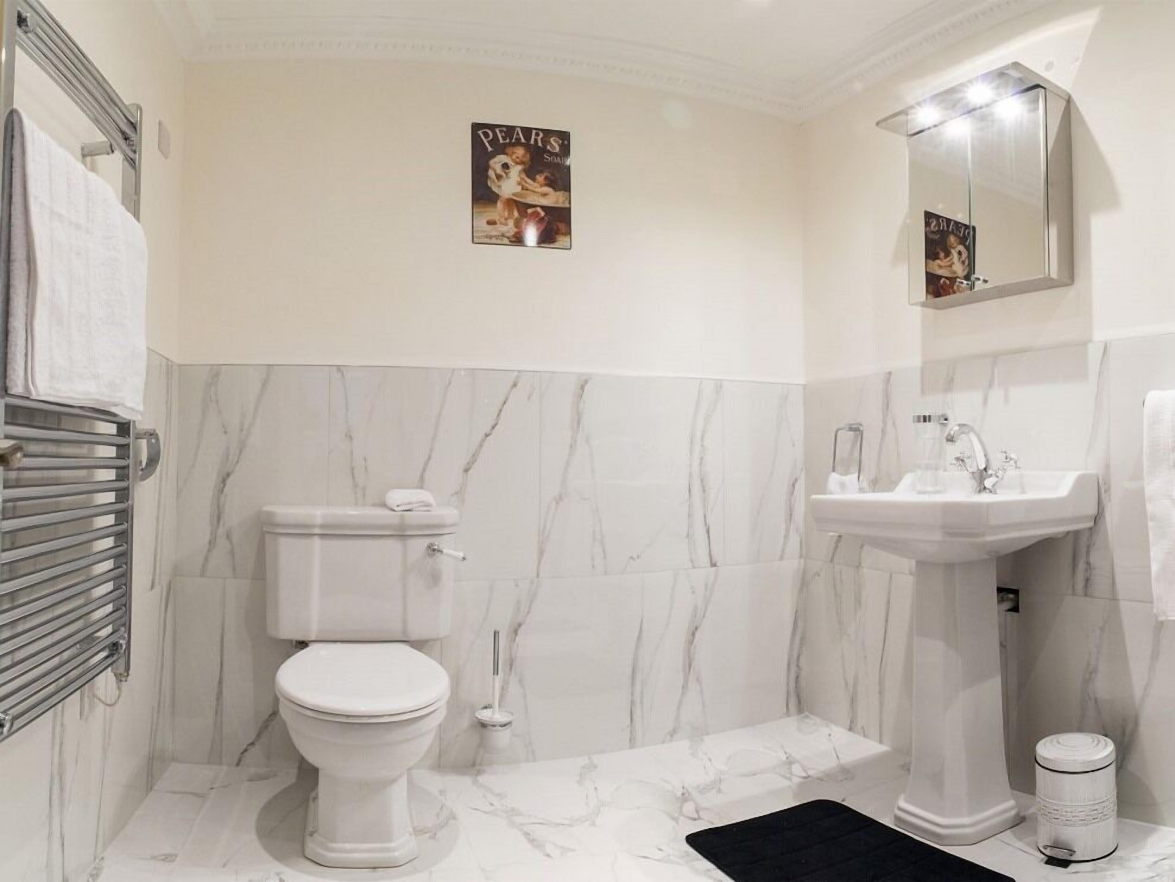 Une salle de bain avec des toilettes, un lavabo et des murs en marbre.