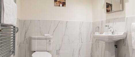 Une salle de bain avec des toilettes, un lavabo et des murs en marbre.