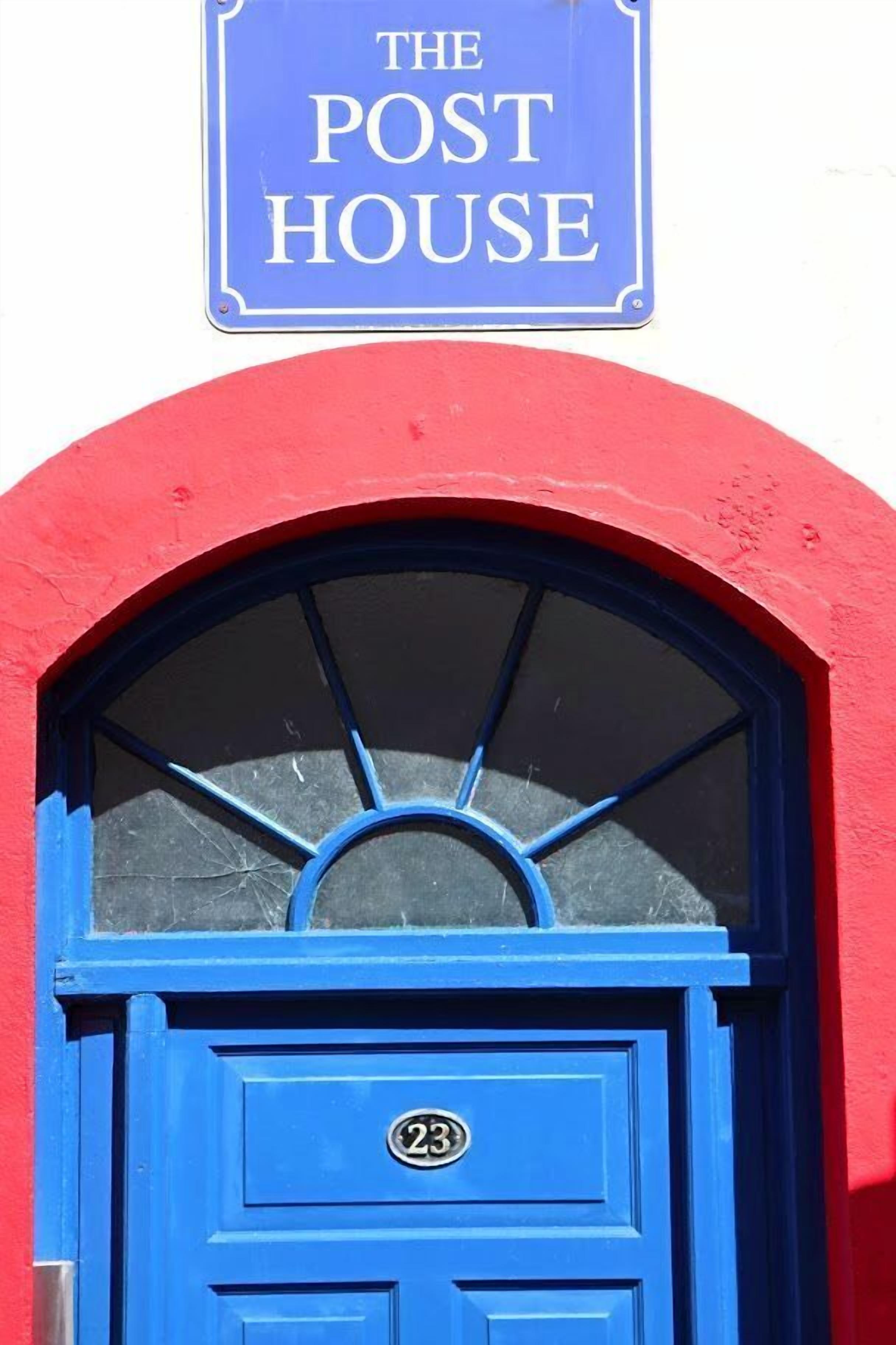 Una puerta azul con una ventana y un letrero encima que dice "THE POST HOUSE".
