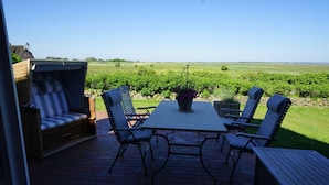 Une terrasse avec une table et des chaises, un banc rembourré et une vue sur un vignoble.