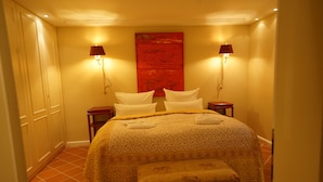 Une chambre d’hôtel avec un lit, deux tables de chevet, un banc et une grande œuvre d’art rouge accrochée au mur.