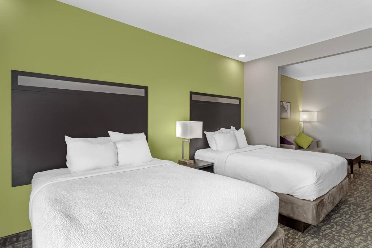 A hotel room with two beds, green walls, and a patterned carpet.
