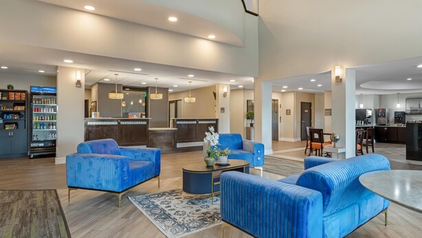 A spacious lobby with blue upholstered sofas, a coffee table, and a dining area. - Best Western Plus Bay City Inn & Suites (Bay City)