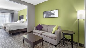 A hotel room with a bed, a sofa, a coffee table, and a lamp. - Best Western Plus Bay City Inn & Suites (Bay City)