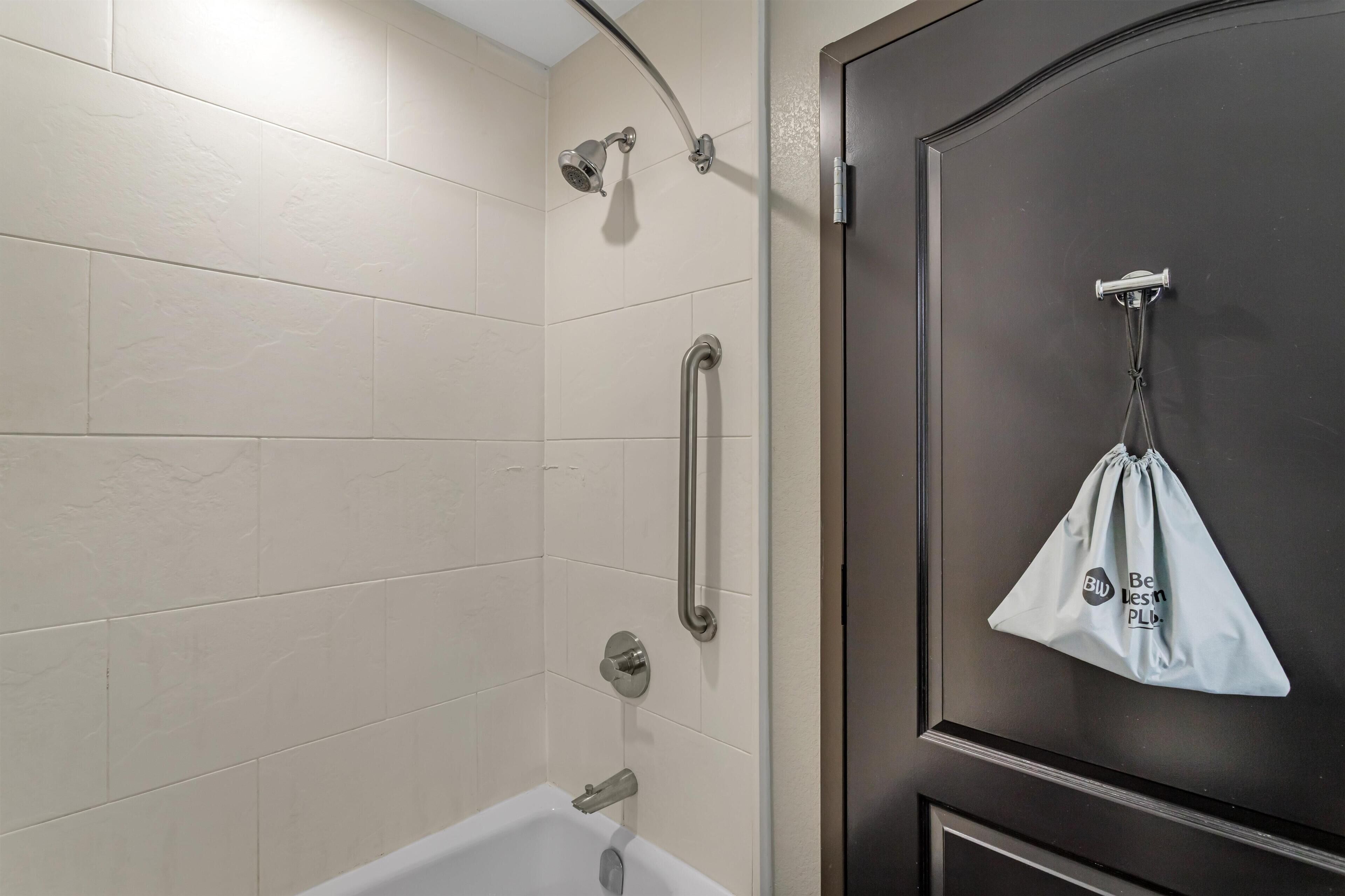 A bathroom with a bathtub, a shower with a handheld showerhead, and a towel hanging on a hook.