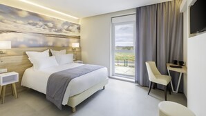 Habitació d'hotel moderna amb un llit gran, una taula de treball, una cadira i un televisor.