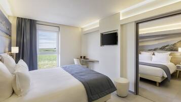 Una habitación de hotel moderna con una cama grande, un escritorio, un televisor y vistas al exterior.