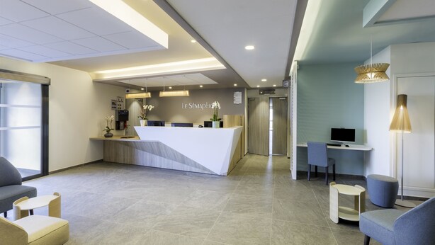 Zona d'estació moderna amb un taulell blanc, seients i una finestra gran.