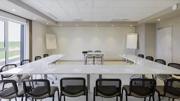 Una sala de conferencias con una larga mesa, sillas, pizarras blancas y vistas al exterior.