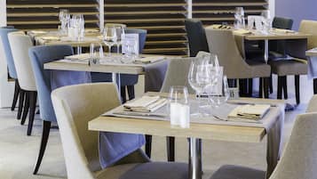 A restaurant with multiple tables, each set with a menu, glasses, and cutlery.