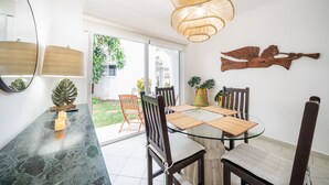 A dining area with a glass table, wooden chairs, and a woven light fixture. - Quintas Pakal 21 by NAS (Playa del Carmen)