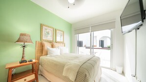 A bedroom with a bed, a nightstand, a lamp, a television, and a window with a view. - Quintas Pakal 21 by NAS (Playa del Carmen)