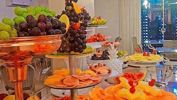 A buffet with various fruits and vegetables, including apples, oranges, and grapes, arranged on multiple serving platters. - Herval Park Hotel (Ponta Pora)