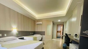 A hotel room with two beds, a desk, a chair, an air conditioning unit, and a trash bin. - Herval Park Hotel (Ponta Pora)