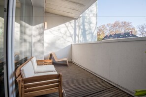 A balcony with wooden furniture and a glass wall. - Appartements in Graz beim LKH (Graz)