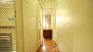 A narrow hallway with a wooden parquet floor leading to a room with a bed. - GoHouse Copacabana 1203 (Rio de Janeiro)