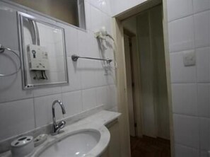 A bathroom with a sink, mirror, towel rack, and toilet paper dispenser. - GoHouse Copacabana 1203 (Rio de Janeiro)