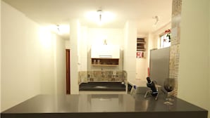 A kitchen with a dark countertop, a wine glass, and a knife holder. - GoHouse Copacabana 204 B (Rio de Janeiro)
