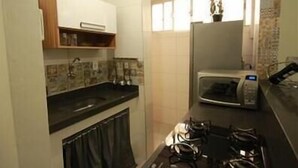 A compact kitchen with a microwave, a sink, and a stove. - GoHouse Copacabana 204 B (Rio de Janeiro)