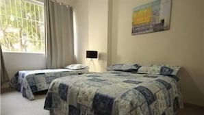 A bedroom with two single beds, a nightstand, a lamp, and a window with curtains. - GoHouse Copacabana 204 B (Rio de Janeiro)