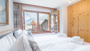 Quarto com uma grande janela, paredes de madeira e uma cama bem arrumada.