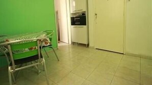 A small kitchen with a green wall, a white door, and a tiled floor.