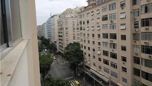 Ein mehrgeschossiges Wohngebäude mit Balkonen, darunter eine Straße und einige Autos.